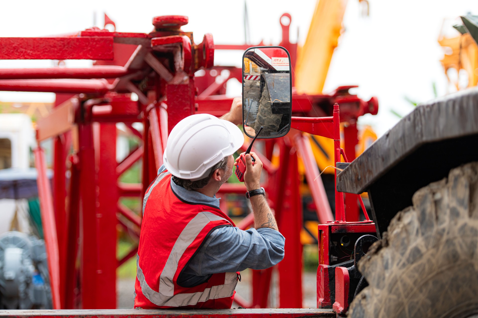 Crane foreman uses walkie-talkie and inspect the construction crane lifting heavy items in the storage warehouse for assembly on the construction site